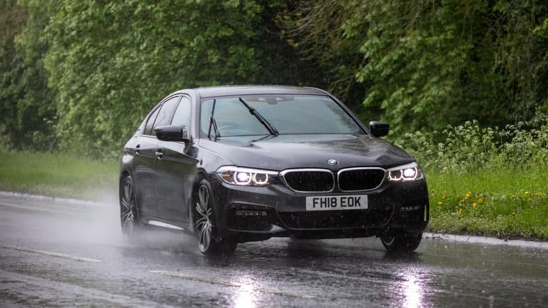 Black BMW 5 Series driving in the rain